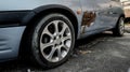 Closeup oldÃ¢â¬â¹ rusty car on the road. Rear car wheel with flat leaky tire on parking. Royalty Free Stock Photo